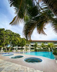 a resort swimming pool with a palm tree at Flat no Carneiros Beach Resort in Tamandaré +47 photos