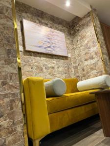 Sofá amarillo en una habitación con pared de ladrillo en Moments Hotel en Yeda