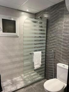 een badkamer met een glazen douche en een toilet bij Moments Hotel in Jeddah
