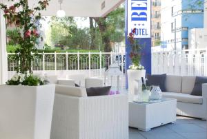 un patio con muebles blancos y plantas en un balcón en Hotel Bel Air, en Riccione