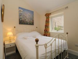 una camera da letto con un letto bianco e una finestra di The Piggery a Macclesfield