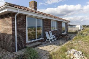 a small brick house with two chairs on a patio at Marie's Cottage, Pagham in Pagham