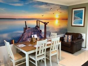 a dining room with a table and a boat on the water at Caedwalla House, Selsey in Selsey