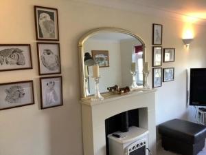 a living room with a fireplace and a mirror at Caedwalla House, Selsey in Selsey