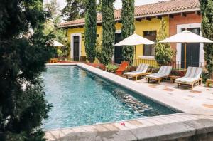 a swimming pool with chairs and umbrellas next to a house at Villa Santa Inés in Antigua Guatemala