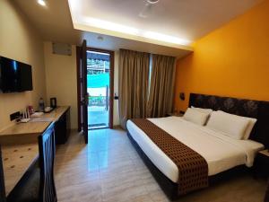 Habitación de hotel con cama grande y escritorio. en Regenta MPG Club Mahabaleshwar, en Mahabaleshwar
