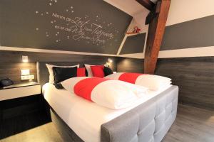 una camera da letto con un grande letto con cuscini rossi e bianchi di MY HOME Hotel Lamm Rottweil "Smart Home" a Rottweil