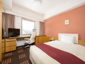 Habitación de hotel con cama, escritorio y TV. en Tachikawa Washington Hotel en Tachikawa