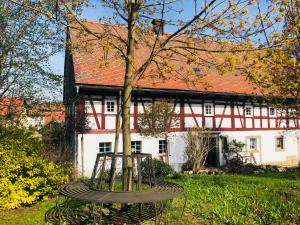 a tree in front of a white house with a building at AuenGut-Bertsdorf in Bertsdorf