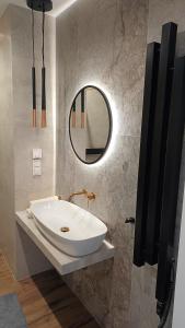 W łazience znajduje się biała umywalka i lustro. w obiekcie Kima Apartament Bażantów 40 w mieście Katowice