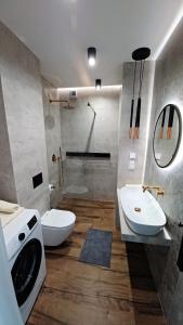 a bathroom with a sink and a toilet and a washing machine at Kima Apartament Bażantów 40 in Katowice +9 photos