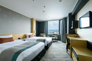 a hotel room with two beds and a flat screen tv at Kanazawa Tokyu Hotel in Kanazawa