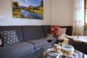 a living room with a couch and two glasses of wine at Ferienwohnung Alpenherz in Obermaiselstein