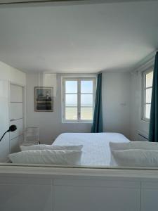
a white bed sitting in a room next to a window at Brise du Large - Maison d'Ault in Ault
