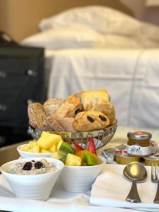 a tray with a basket of bread and bowls of fruit at Hotel Adriatica in Geneva
