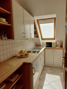 eine Küche mit weißen Schränken und einem Fenster in der Unterkunft Tölgyes Apartment in Hajdúszoboszló