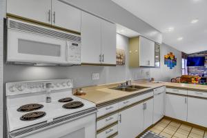 una cocina con armarios blancos y un horno de fogón blanco en Fairway Heights condo, en Branson