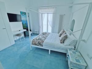 a white bedroom with a bed and a desk at Solecore Amalficoast in Conca dei Marini