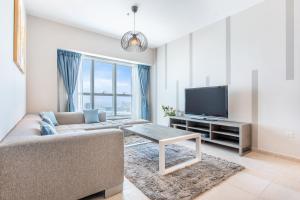 sala de estar con sofá y TV en Icon Casa Living - Elite Residence Tower, en Dubái