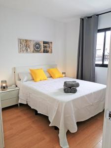 sypialnia z dużym białym łóżkiem i żółtymi poduszkami w obiekcie La Casita del Sol w Corralejo