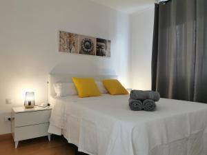 sypialnia z białym łóżkiem z żółtymi poduszkami w obiekcie La Casita del Sol w Corralejo +30 zdjęć