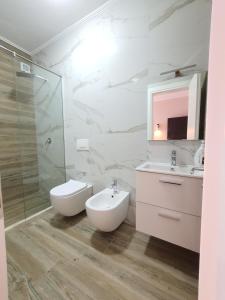 een badkamer met een wastafel, een toilet en een spiegel bij Villa Olympia in Durrës