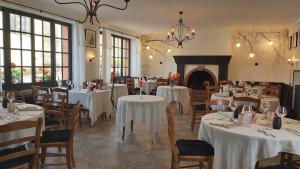 a restaurant with tables and chairs with white tablecloths at Logis- Hôtel & Restaurant Le Montligeon in La Chapelle-Montligeon