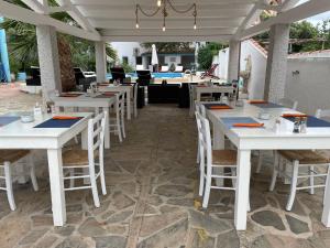 a restaurant with white tables and chairs on a patio at Villa Dessena Guest House in Cala Liberotto