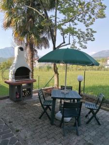 einen Tisch mit einem Regenschirm neben einem Pizzaofen in der Unterkunft Colori nel parco in Cesiomaggiore