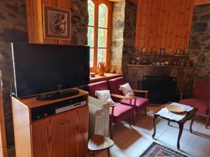 ein Wohnzimmer mit einem Flachbild-TV und lila Stühlen in der Unterkunft Elpiniki's Old House in Kalopanagiotis