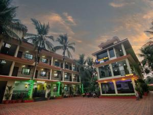 un grand bâtiment avec des palmiers devant lui dans l'établissement Shrikrishna Studio Goa, à Goa Velha
