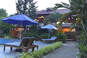 a patio with chairs and umbrellas next to a house at Rain Forest Resort Phu Quoc in Phu Quoc