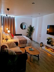 Superbe appartement privé avec jacuzzi في Saint Etienne: غرفة نوم بسرير واريكة وطاولة