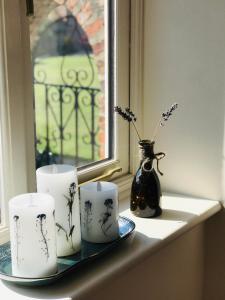 林肯Charming Hen Cottage Countryside Retreat Lincoln的窗台,有三个蜡烛和一个花瓶