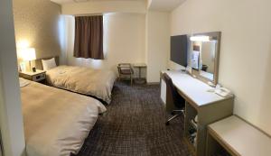 ein Hotelzimmer mit 2 Betten und einem Schreibtisch in der Unterkunft Hotel Yassa in Mihara