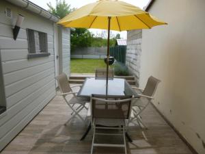 - une table et des chaises avec un parasol jaune sur la terrasse dans l'établissement maison du haut pont, à Saint-Omer