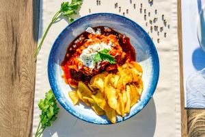 a blue bowl of food with pasta on a table at Agnanti in Parga