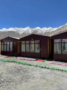 a building with snow covered mountains in the background at Pangong Delight Camps and Cottages in Spangmik