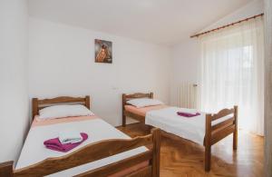 two beds in a room with white walls and wooden floors at Plava Adria Podstrana in Podstrana