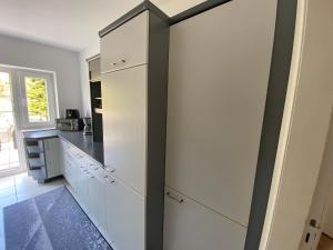 a kitchen with white cabinets and a black door at Ferienwohnung mit Balkon und Garten OG in Flensburg