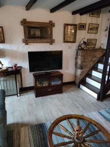 a living room with a flat screen tv and a wooden wheel at Fishermen's cottage with log burner, 2 bathrooms & sea views from garden terraces in The Mumbles