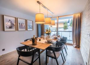 uma sala de jantar com uma mesa de madeira e cadeiras em Luxueux appartement skis aux pieds, jacuzzi privatif em Courchevel