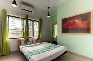 a bedroom with a large bed with green curtains at Ecoville suites in Kozhikode
