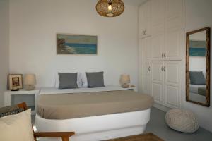 a white bedroom with a bed and a mirror at Zefiros in Karavostasi