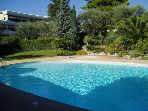 une grande piscine bleue à côté d'une plage dans l'établissement 80m2 dans Parc Classé, Piscine, Calme, 5mn de Cannes, au Cannet