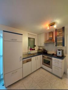 an empty kitchen with white cabinets and a sink at FeWo zwischen Freiburg und Europa Park Rust nur 200m zur S-Bahn in Bahlingen