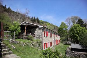 a stone building with red windows and a mountain at Servigliana in Popiglio