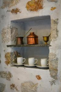 un estante con tazas en la pared en Maistros, en Karavostasi