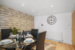 una sala da pranzo con tavolo, sedie e orologio di Luxnightzz - Stylish Boutique 1 Bed Apartment a Gravesend