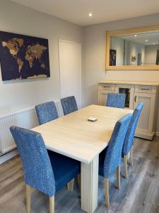 a conference room with a wooden table and blue chairs at Spacious & modern 3 bed house in Stafford +7 photos